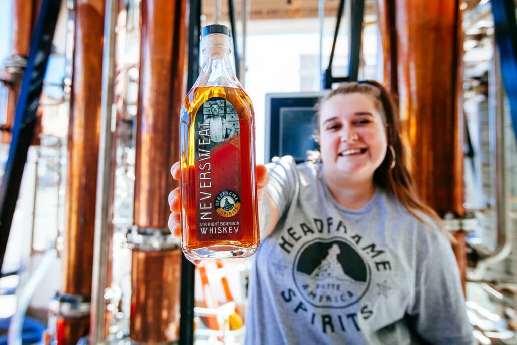 Bartender holding a spirits bottle at a bar in Butte, Montana, showing authentic business photography over stock images.