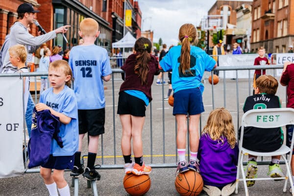 Kids watching Uptown Hoops from behind a barricade during a community street basketball event in Uptown Butte, Montana.
