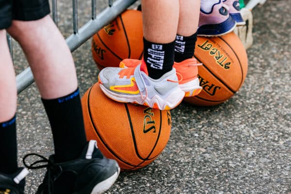 Close-up detail of kids standing on basketballs while watching a youth street basketball event in Butte, Montana.