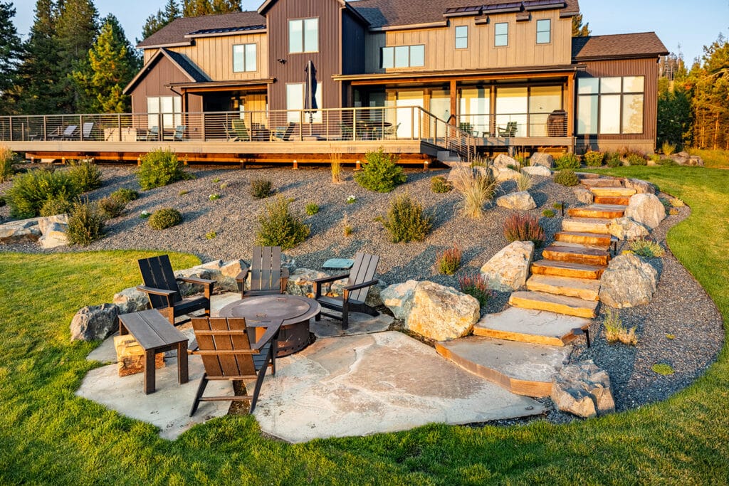 Fire pit surrounded by stonework and landscaped plantings at a modern Montana home
