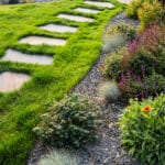 Grass-inlaid stone pathway with mature plantings in a professionally designed landscape