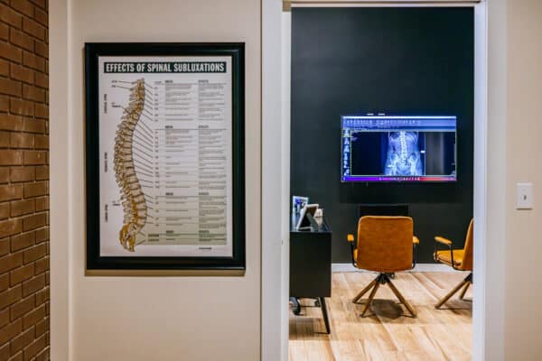 Brand photography of a chiropractic consultation room in Butte, Montana, featuring patient seating and diagnostic imaging.