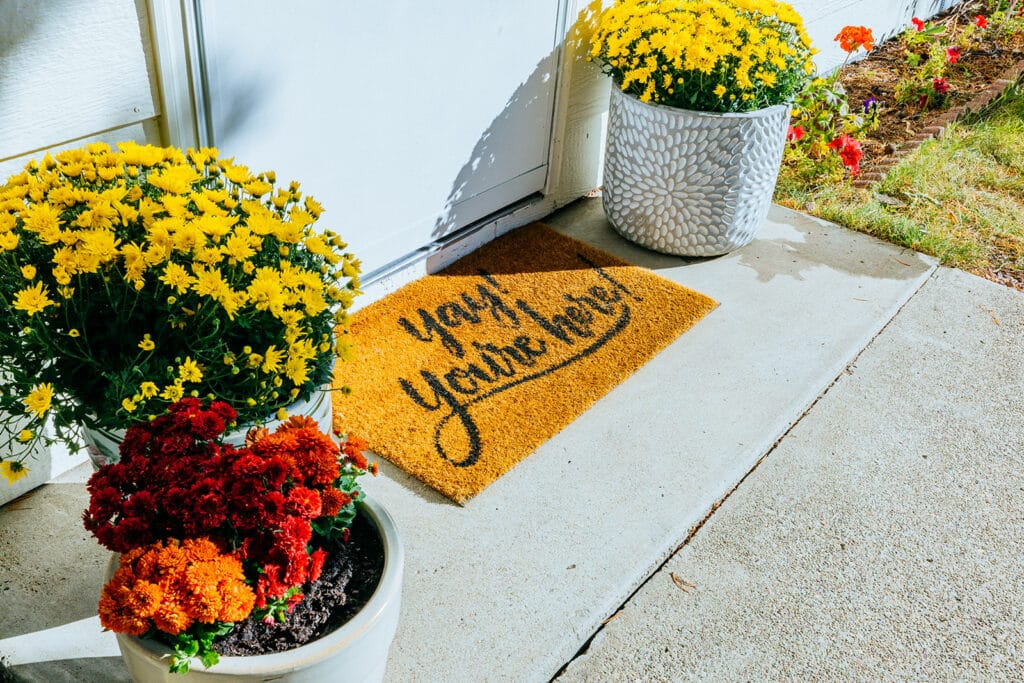 Glacier Airbnb Photography featuring warm welcome mat surrounding by flowers reading: yay! you're here!