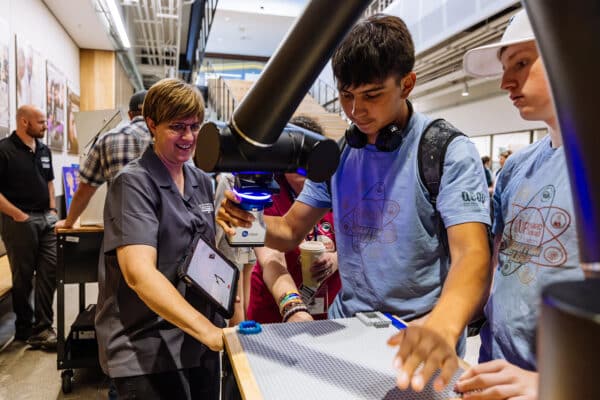 Instructor guides a student through robotics programming during a STEM education program photographed for Finn Partners.