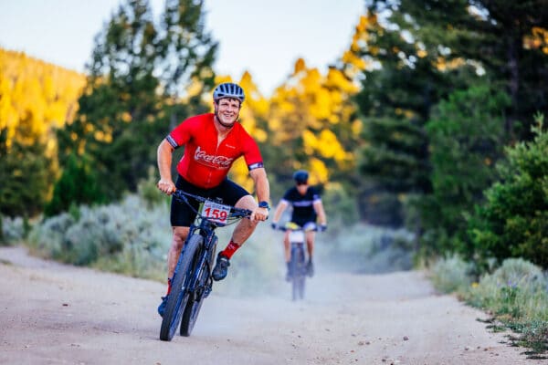 Butte photography of Butte 100 racer smiling and posing at camera while while riding bike