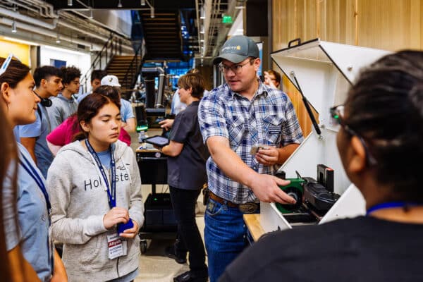Instructor explains robotics machinery to students during a STEM education event photographed in Montana.